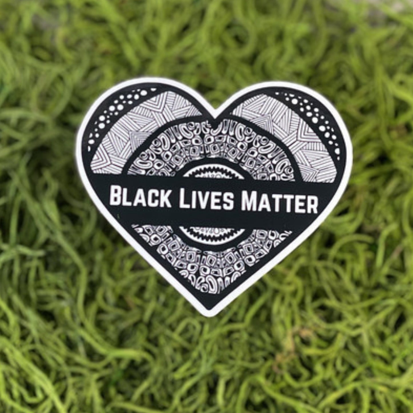 A heart-shaped sticker with "Black Lives Matter" written on it. Waterproof, dishwasher-safe, and weatherproof for long-lasting support.