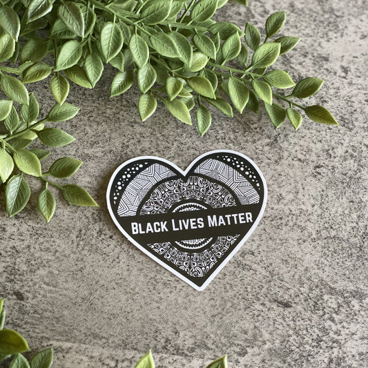 A heart-shaped sticker with "Black Lives Matter" written on it. Waterproof, dishwasher-safe, and weatherproof for long-lasting support.
